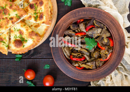 Warmer Salat von Leber und Paprika in einem Ton Schüssel auf einem dunklen Holztisch. Gebratene Leber. Die Ansicht von oben Stockfoto