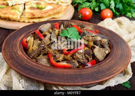 Warmer Salat von Leber und Paprika in einem Ton Schüssel auf einem dunklen Holztisch. Gebratene Leber. Stockfoto