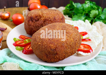 Saftige goldene Schnitzel gefüllt mit gekochtem Ei auf einer hölzernen Hintergrund. Stockfoto