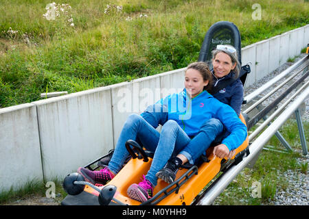 Mutter und Tochter genießen Sie eine Fahrt mit dem Alpine Coaster, Sommerrodelbahn an der Kolbensattelhütte in der Nähe von Oberammergau. Stockfoto