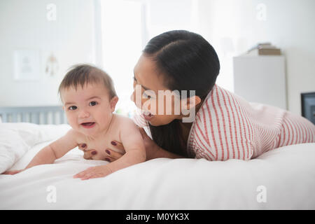 Mutter spielt auf dem Bett mit Baby Sohn Stockfoto
