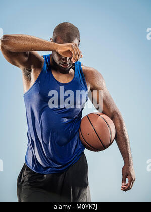 Schwarzer Mann holding Basketball Schweiß von der Stirn wischen