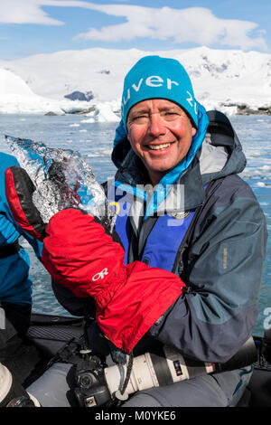 Expedition Mitglied in Zodiac Boot hält kristallklare Gletschereis; Zodiacs shuttle alpinen Bergsteigen Skifahrer in die Antarktis aus dem Passagierschiff Stockfoto