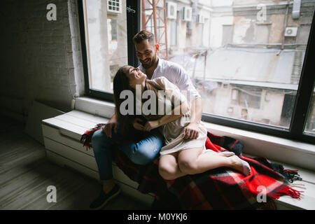Kaukasische Paar kuscheln auf der Bank in der Nähe der Fenster Stockfoto