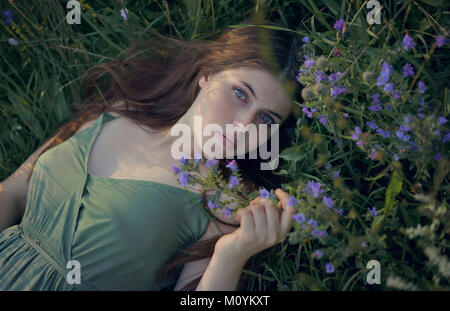 Kaukasische Frau Festlegung im Gras mit Wildblumen Stockfoto