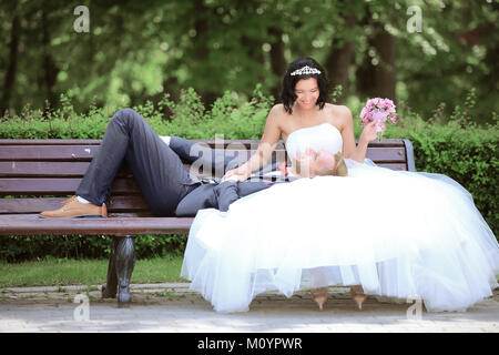 Braut und Bräutigam auf einer Parkbank Stockfoto