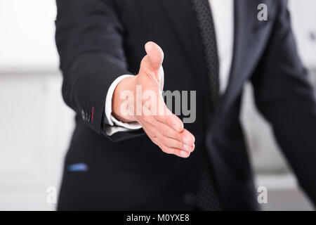 Unternehmer, die sich mit der offenen Hand mit Handschlag und einladend für Zusammenarbeit Stockfoto