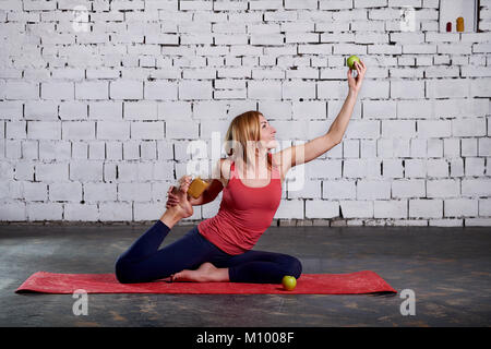 Yoga Vegetarismus. Yoga Mädchen hält Smoothies und Apple. Konzept des gesunden Lebens. Sportliche hübsche Frau liebt Sport. Stockfoto