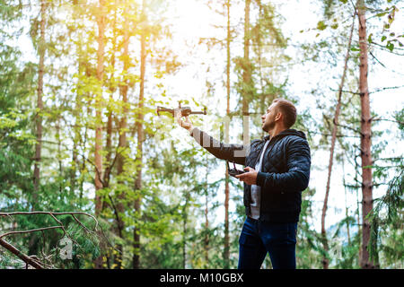 Guy startet einen quadrocopter im Wald Stockfoto