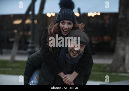 Ein junges Paar, das Spaß im Freien im Winter. Tragen warme Kleidung, Hüte und Schals. Besuch Weihnachtsmarkt in Wien, Österreich. Alles ist de Stockfoto