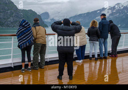 Kleine Gruppe von Passagieren an Deck Geländer mit Blick auf die malerische Landschaft auf Alaska Kreuzfahrt - Glacier National Park, Alaska Stockfoto