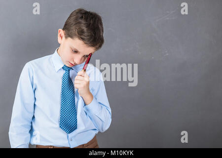 Unsicher junge Student vor dem dunklen Hintergrund mit copy-Raum als Tafel Stockfoto