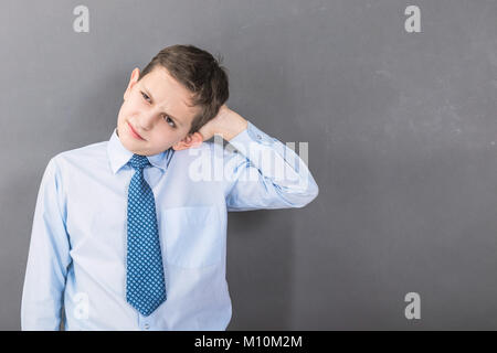 Unsicher junge Student vor dem dunklen Hintergrund mit copy-Raum als Tafel Stockfoto