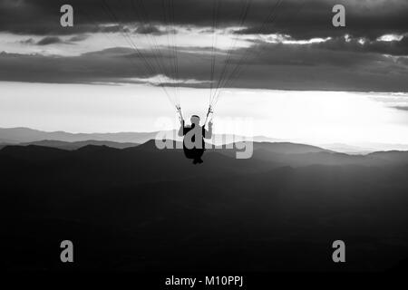 Schöne aufnahme eines Gleitschirms silhouette Fliegen über Monte Cucco (Umbrien, Italien) mit Sonnenuntergang im Hintergrund Stockfoto