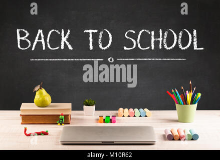 Zurück zum Konzept der Schule mit dem Schreiben auf Tafel in Großbuchstaben und einem Schreibtisch mit Papieren, Obst Stockfoto