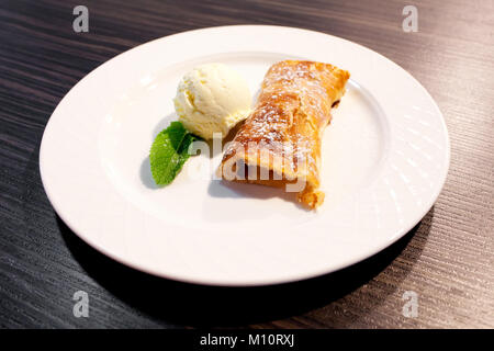 Apfelstrudel und Eis auf der Platte Stockfoto