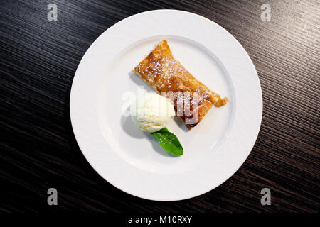 Apfelstrudel und Eis auf der Platte Stockfoto