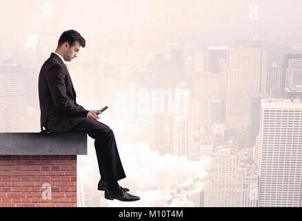 Eine elegante Geschäftsmann in der modernen Anzug sitzt auf der Spitze der aus Ziegeln, über das Stadtbild mit Wolken Konzept suchen Stockfoto