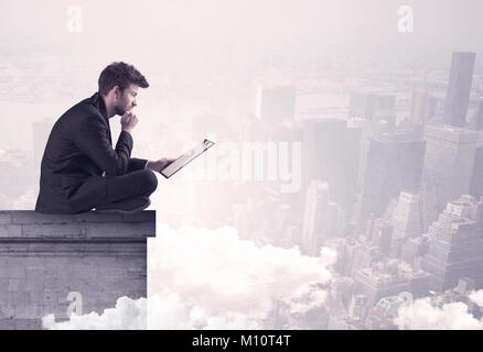 Eine elegante junge Unternehmer sitzen am Rande Blick über Stadt Landschaft mit Wolken Konzept Stockfoto