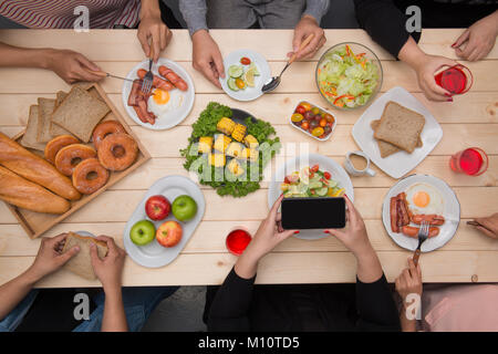 Abendessen mit Freunden genießen.  Draufsicht der Gruppe von Menschen, die Abendessen zusammen beim Sitzen am Tisch aus Holz Stockfoto