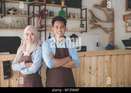 Erfolgreiche zwei Coffee shop besitzer Stehen mit verschränkten Armen mit Partner Stockfoto