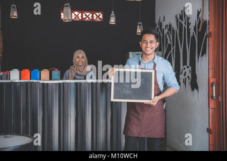 Coffee shop Kellner holding Blackboard Zeichen vor seinem Café Stockfoto