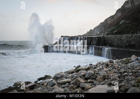 Wellen über die beschädigten Hafenmauer in Lamorna Cove brechen Stockfoto