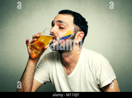 Lustig sport Fan mit Fahne gemalt auf Gesicht Bier trinken. Stockfoto