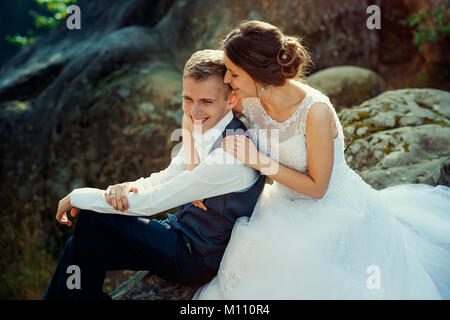 Sensible Porträt der Schönen fröhlichen jungvermählte Paar sanft umarmen auf dem Felsen. Stockfoto