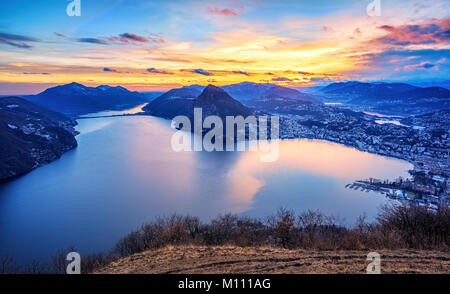 Dramatischer Sonnenuntergang über dem Luganer See in den Schweizer Alpen, Tessin, Schweiz Stockfoto