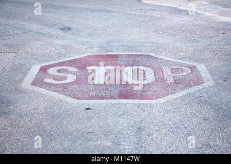 Verwitterte rot Hexagon Stoppschild auf der Straße Bürgersteig Oberfläche lackiert, closeup Hintergrund. Stockfoto