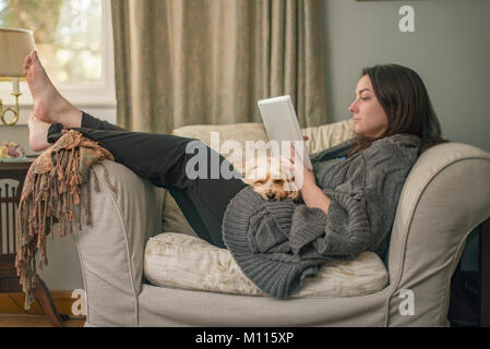 Frau Entspannung mit der Tablette und Hund Stockfoto