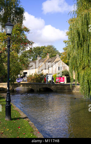 Bourton-on-the-Water, England - Oktober 7 2010: Besucher und Touristen nutzen Sie die Herbst Sonnenschein in "das Venedig der Cotswolds" als Bourton-on-the-Water ist manchmal genannt. War der früheste der fünf lokalen Steinbrücken im Jahr 1654 gebaut. UK, Gloucestershire, Cotswolds, Bourton-on-the-Water. Touristen genießen Herbst Sonnenschein durch den Fluss. Stockfoto