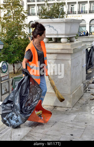 Frau street Cleaner mit Kehrblech und Besen zusammen mit schwarzen Wurf Beutel, gut sichtbare Weste in Athen arbeiten Stockfoto