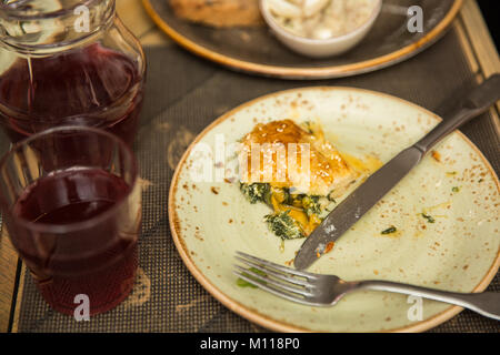 Khachapuri mit Spinat, Ei und Käse auf der alten Platte. Kanne mit Kompott. Reste Stockfoto