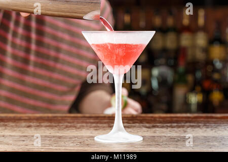 Cocktail Cosmopolitan, der Barkeeper, gießt auf der Bar. Cocktail auf der Basis von Wodka, Liköre Triple Sec, Zitrone und Cranberry Saft. Platz für Text Stockfoto