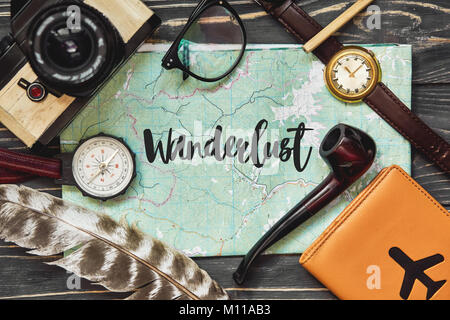 Wanderlust text Zeichen auf Karte anzeigen. travel Concept, hipster Flach. Pass Kompass und Brille Foto Kamera Leitung auf schwarzem Hintergrund Holz Draufsicht. Pla Stockfoto