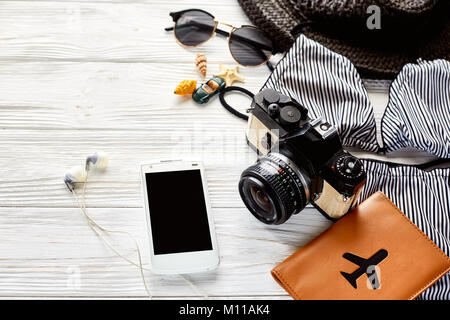 Hallo Sommerurlaub Konzept. Elegante Badeanzug, Hut und Sonnenbrille schalen Reisepass Telefon Foto Kamera auf weißem Holz- Hintergrund, Ansicht von oben. Platz für Stockfoto