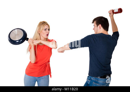 Junge wütend Paar Kämpfen mit Pfanne und Flasche gegen den weißen Hintergrund Stockfoto