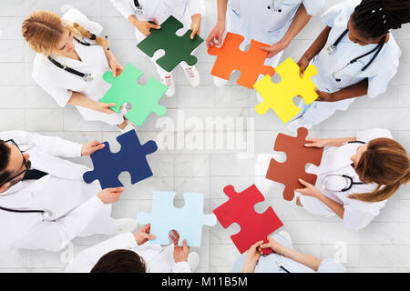 Ansicht der Ärzte im Kreis halten bunte Puzzle stehend im Krankenhaus Stockfoto