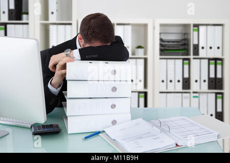 Geschäftsmann Schlafen auf Stapel von Ordner in Office Stockfoto