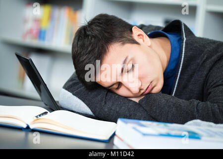 Müde Schüler schlafen in Bibliothek Stockfoto