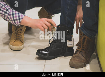 Mom wählt winter Schuhe für ihre Tochter in den Store. Stockfoto