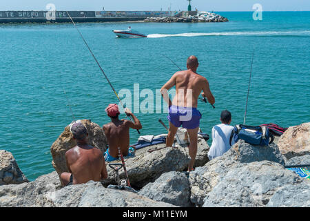 Männer angeln am Ende der Pier in Viareggio, Toskana, Italien. Stockfoto