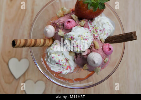 Über dem Kopf fotografie Ansicht einer köstlichen Sommer Erdbeeren Eisbecher in einem Glas Schale mit Obst baiser Sahne und Schokolade Stockfoto