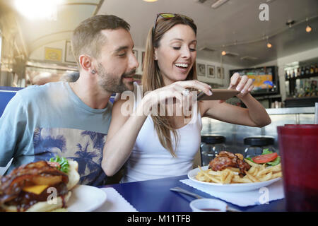 Junges Paar in Fast-Food-Restaurant unter Bild von Burger Stockfoto