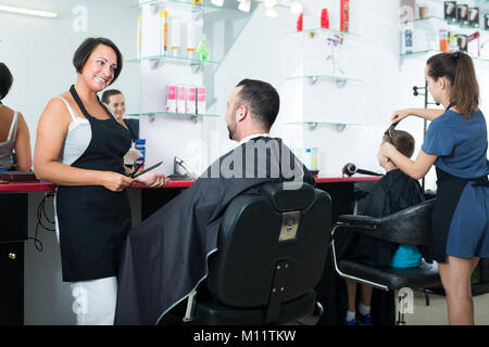 Positive reifen weiblichen professionellen Friseur zu männlichen Klienten im Beauty Salon chatten Stockfoto