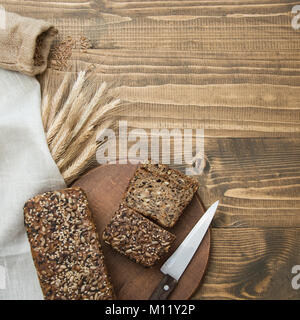 Fitness Brot. Ein Laib frisches rustikale Mahlzeit Roggenbrot, auf einem Holzbrett, ländliche essen Hintergrund geschnitten. Ansicht von oben. Kopieren Sie Platz. Quadratisches Bild. Stockfoto