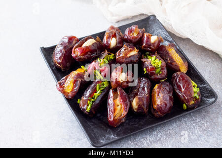 Gefüllte Datteln mit Muttern und kandierten Früchten füllen auf einen Stein oder Schiefer Hintergrund. Das Konzept einer gesunden Nachtisch. Stockfoto