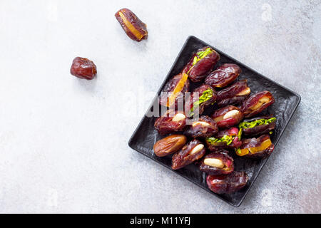 Gefüllte Datteln mit Muttern und kandierten Früchten füllen auf einen Stein oder Schiefer Hintergrund. Das Konzept einer gesunden Nachtisch. Stockfoto